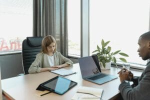 A diverse job interview scenario in a modern office setting with a laptop and documents on the table.